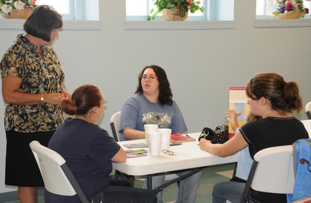 Dr. Pat Cowherd, standing, dean of the School of Business and Economics at CU, talks with, from left, Crystal Arnold, with her son Aron, of Summersville, Miranda Whitlow of Mt. Sherman, and Kandy House of Magnolia. (Campbellsville University Photo by Ashley Zsedenyi)